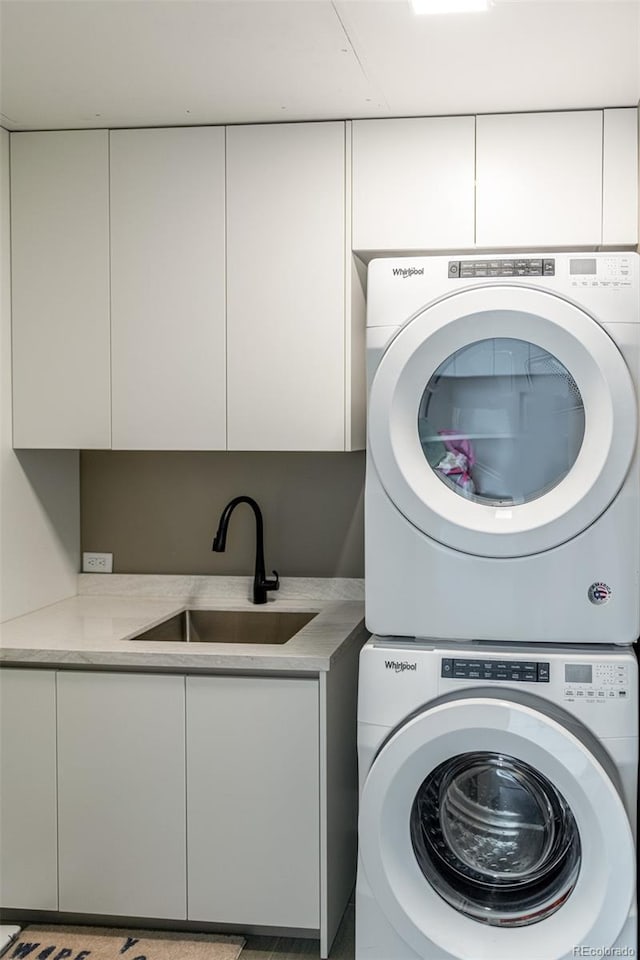 laundry room featuring stacked washing maching and dryer, a sink, and cabinet space