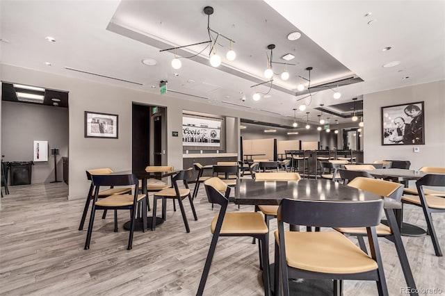 dining area featuring light wood-style flooring and a tray ceiling