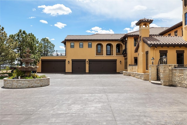 mediterranean / spanish-style home with an attached garage, stucco siding, a tiled roof, and concrete driveway