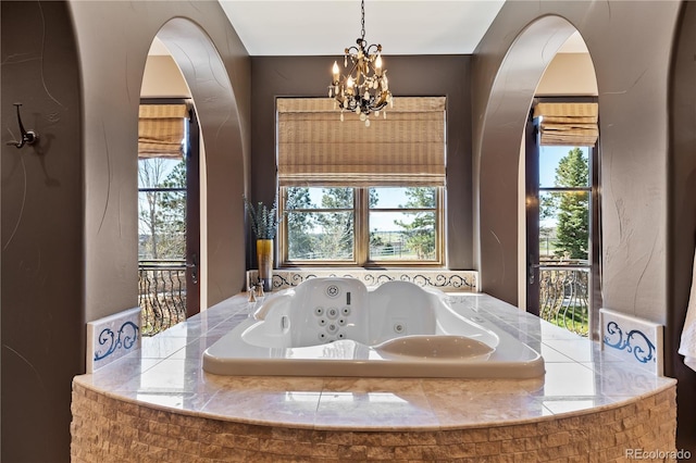 bathroom featuring a wealth of natural light, a whirlpool tub, and a chandelier