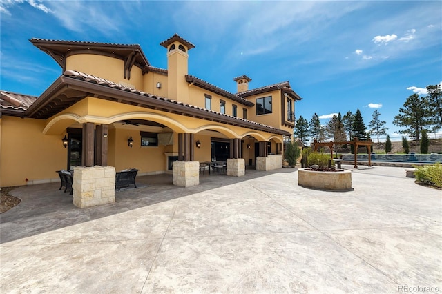 rear view of property featuring outdoor dining area, stucco siding, and a patio