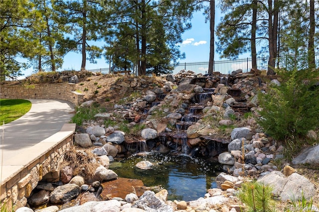 view of home's community with a small pond and fence