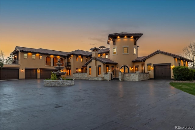 mediterranean / spanish home featuring driveway, a tile roof, and stucco siding
