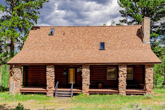 log-style house featuring stone siding, roof with shingles, and a chimney