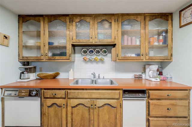 kitchen with tasteful backsplash, light countertops, glass insert cabinets, white dishwasher, and a sink