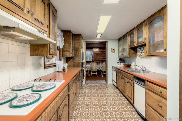 kitchen featuring white electric stovetop, decorative backsplash, glass insert cabinets, a sink, and under cabinet range hood