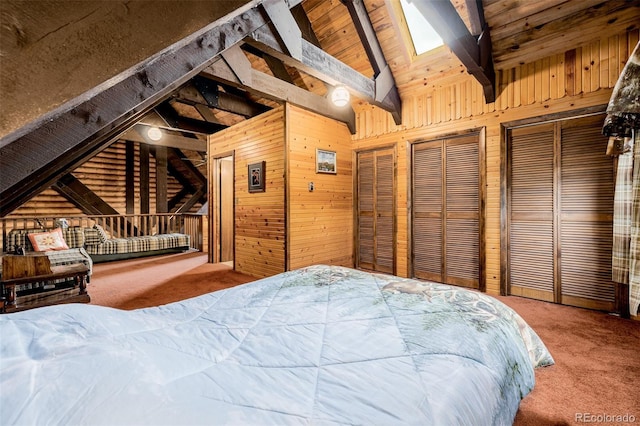 bedroom with carpet, vaulted ceiling with beams, two closets, wood ceiling, and wood walls