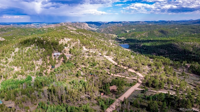 birds eye view of property featuring a view of trees and a water and mountain view