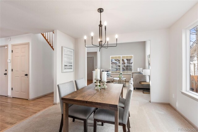 dining room featuring light wood-style floors, light carpet, baseboards, and an inviting chandelier