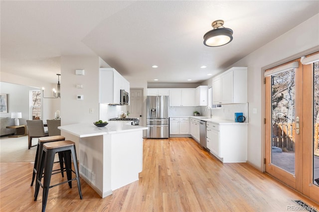 kitchen featuring appliances with stainless steel finishes, white cabinets, light countertops, and a kitchen breakfast bar