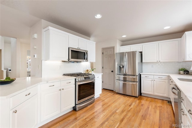 kitchen with stainless steel appliances, recessed lighting, backsplash, white cabinets, and light wood-type flooring