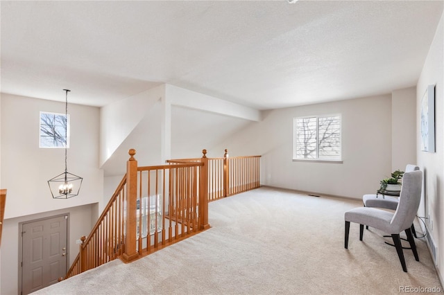 sitting room with light carpet, a textured ceiling, an upstairs landing, and an inviting chandelier