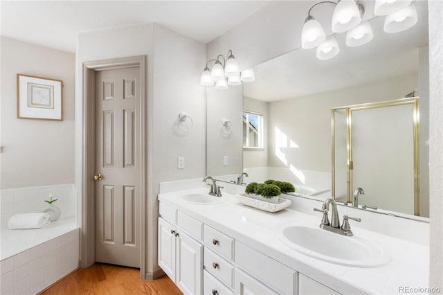 full bath featuring a garden tub, double vanity, wood finished floors, and a sink