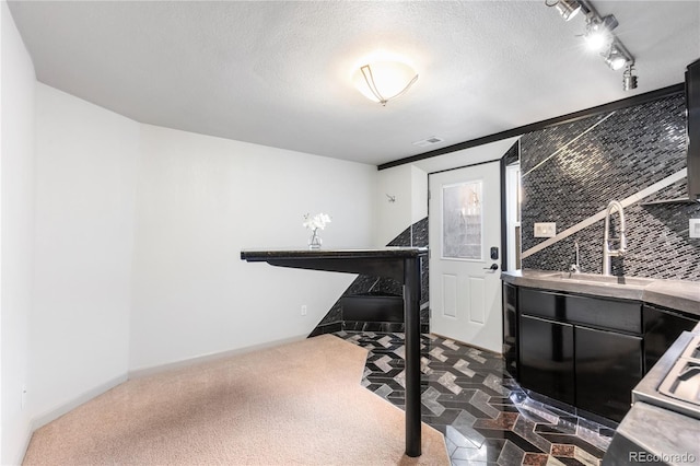 miscellaneous room featuring rail lighting, visible vents, a sink, and a textured ceiling