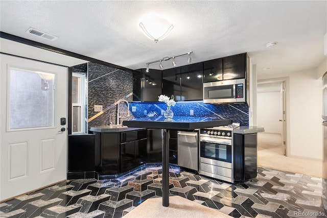 kitchen featuring dark countertops, appliances with stainless steel finishes, a textured ceiling, modern cabinets, and dark cabinets