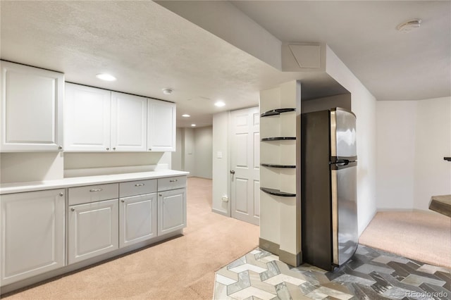 kitchen featuring recessed lighting, light colored carpet, light countertops, freestanding refrigerator, and white cabinets