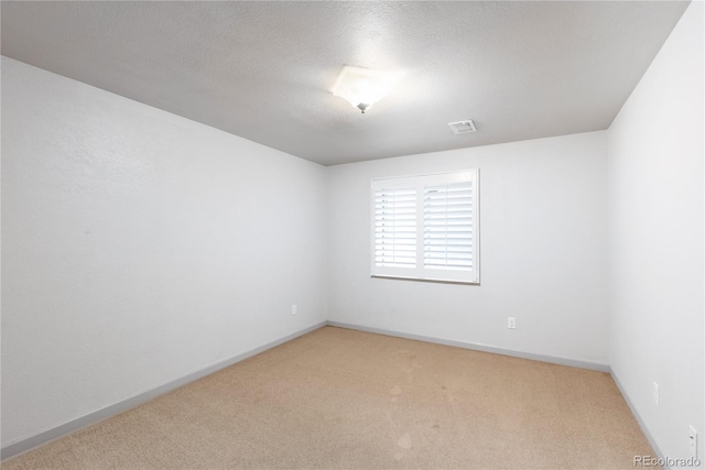 empty room with visible vents, carpet flooring, a textured ceiling, and baseboards