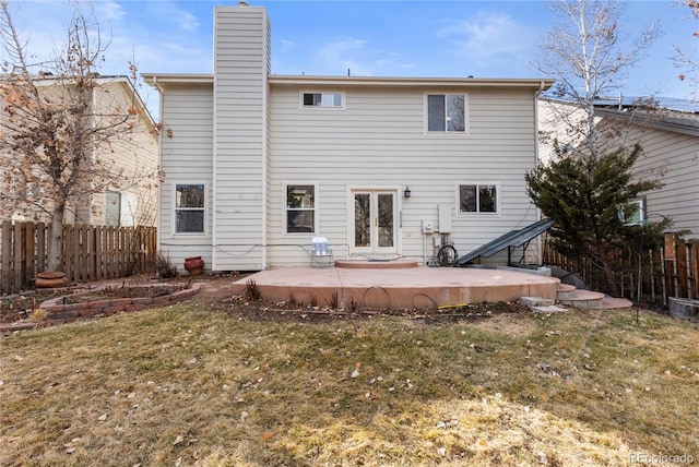 rear view of house featuring a lawn, fence, a chimney, and a patio