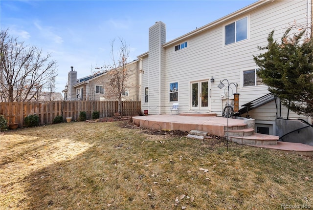 rear view of property featuring a patio, a lawn, and fence