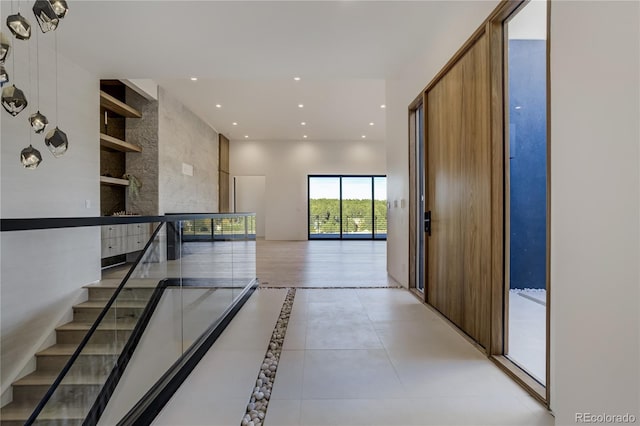 hallway featuring built in shelves, light tile patterned flooring, a towering ceiling, and recessed lighting