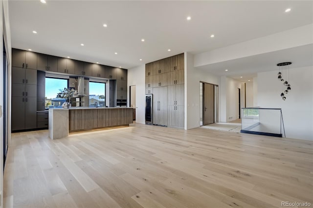 kitchen with recessed lighting, open floor plan, a kitchen island with sink, modern cabinets, and light wood-type flooring