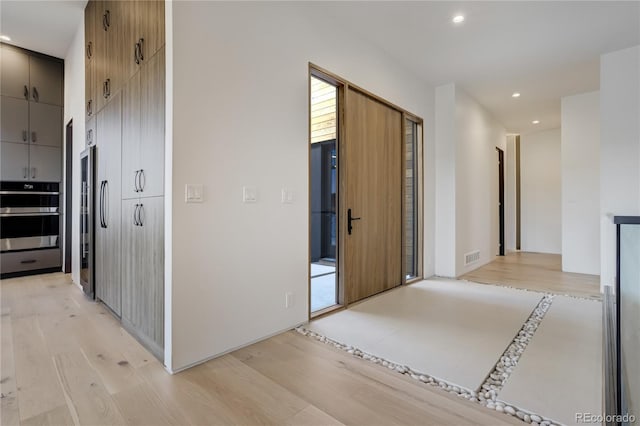 corridor with light wood-type flooring, visible vents, and recessed lighting