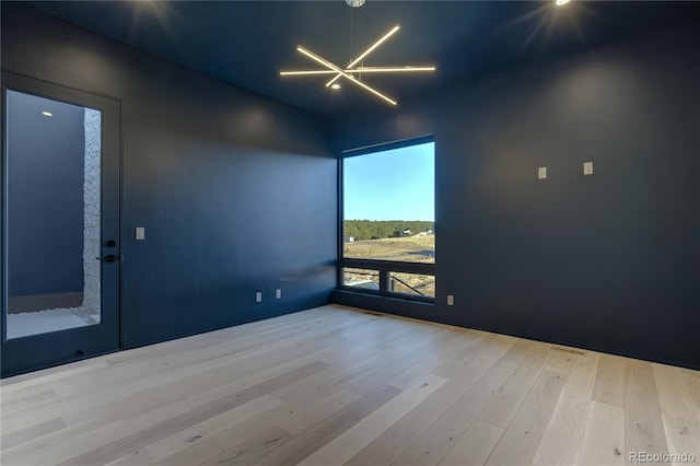 empty room featuring a notable chandelier and wood finished floors