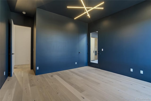 empty room featuring an inviting chandelier and wood finished floors