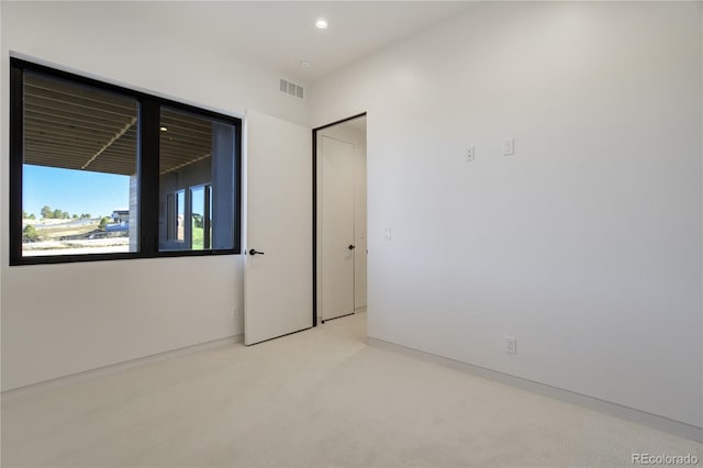 spare room featuring light colored carpet, visible vents, and recessed lighting