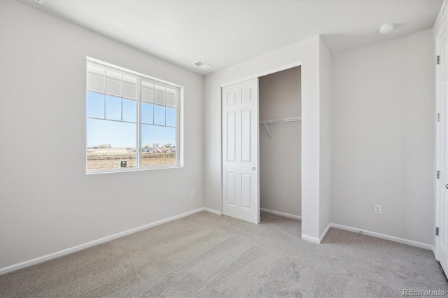 unfurnished bedroom featuring light carpet and a closet