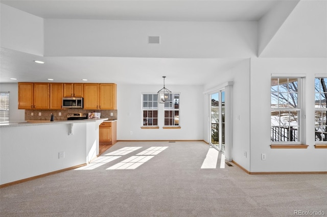 kitchen with stainless steel appliances, decorative light fixtures, light colored carpet, a healthy amount of sunlight, and backsplash