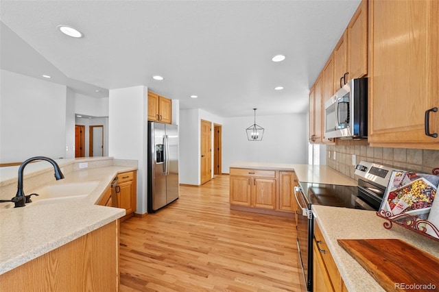 kitchen featuring appliances with stainless steel finishes, sink, pendant lighting, and kitchen peninsula