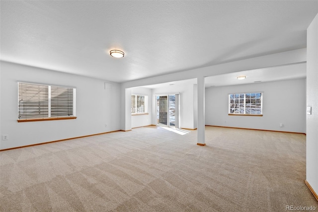 unfurnished living room featuring light colored carpet and a textured ceiling