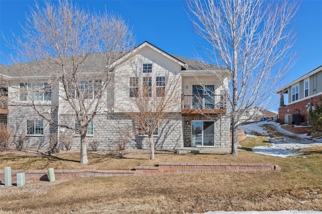 view of front of property with a balcony, central AC, and a front lawn