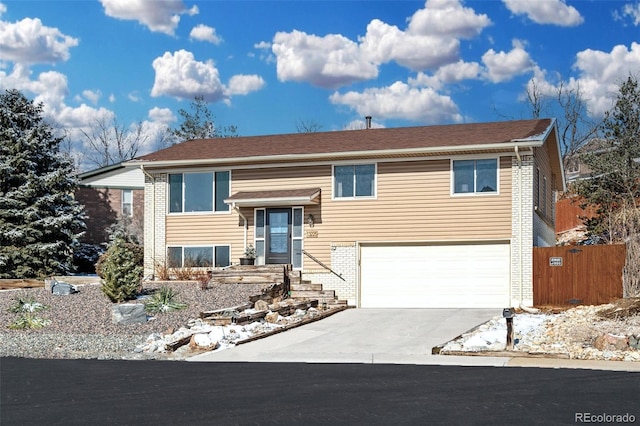 bi-level home with driveway, a garage, and brick siding