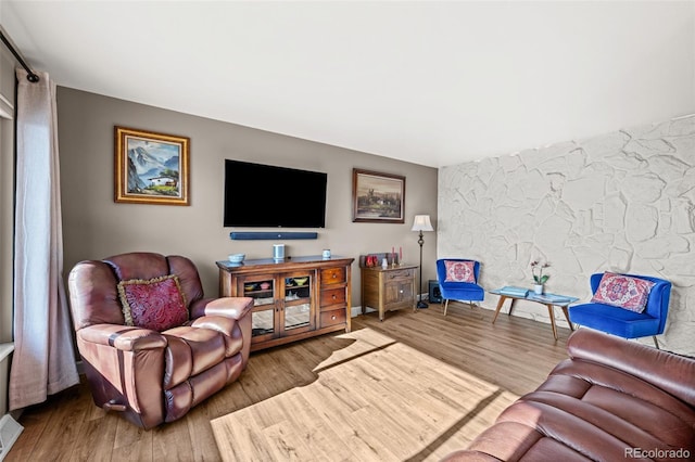 living room with an accent wall, wood finished floors, and visible vents