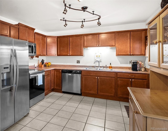 kitchen featuring brown cabinets, stainless steel appliances, a sink, and light countertops