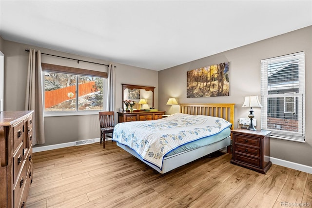 bedroom featuring visible vents, light wood-style flooring, and baseboards