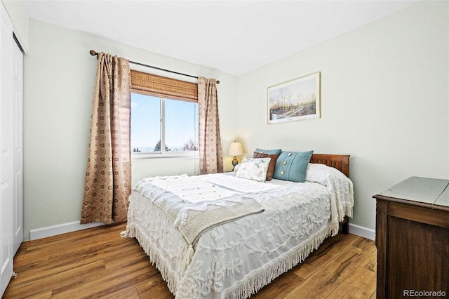 bedroom with a closet, baseboards, and wood finished floors