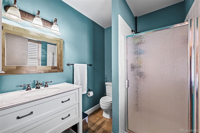 full bathroom with baseboards, toilet, wood finished floors, vanity, and a shower stall