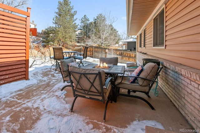 snow covered patio featuring fence, a fire pit, and outdoor dining space