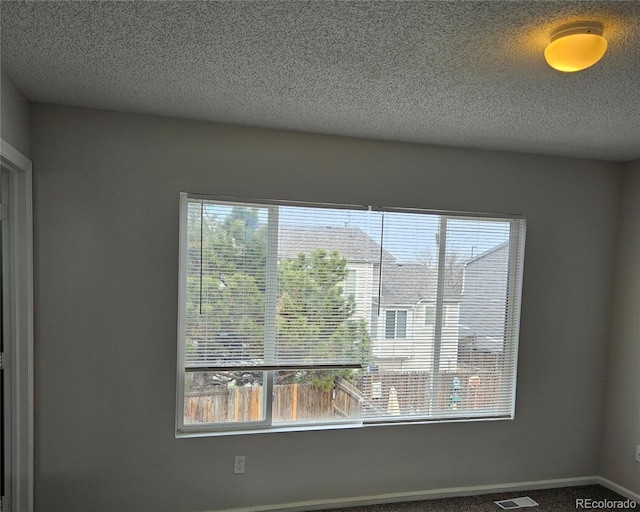 room details featuring visible vents, baseboards, a textured ceiling, and carpet flooring