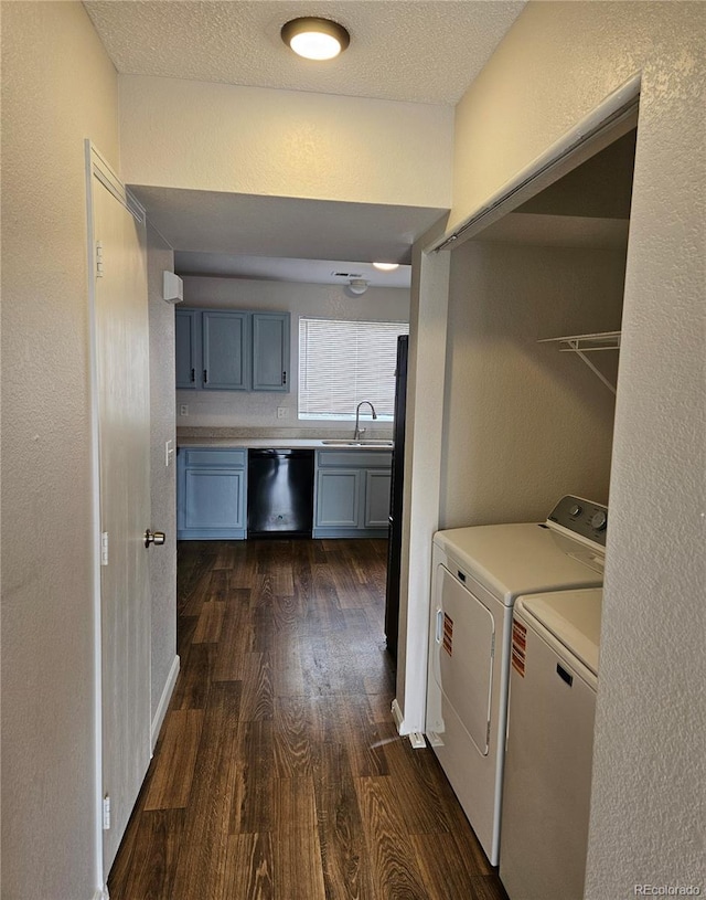 clothes washing area with independent washer and dryer, a sink, a textured ceiling, dark wood-style floors, and laundry area