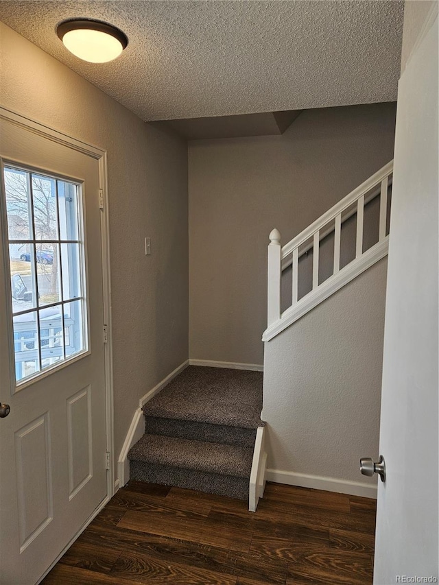 stairway with wood finished floors, baseboards, and a textured ceiling