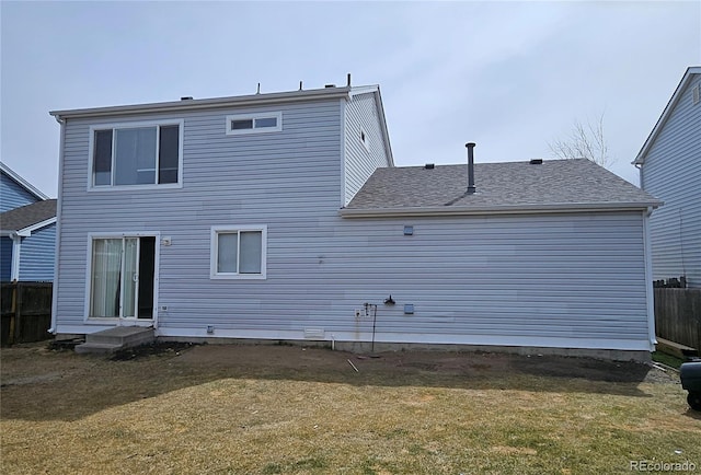 back of house with a lawn, a shingled roof, entry steps, and fence