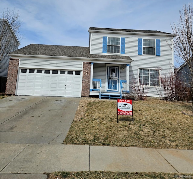 traditional home featuring a porch, an attached garage, driveway, and a front lawn