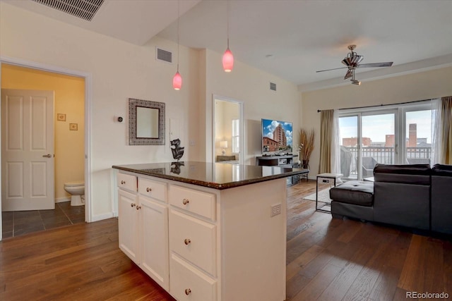 kitchen featuring dark stone counters, white cabinetry, hanging light fixtures, and dark hardwood / wood-style floors