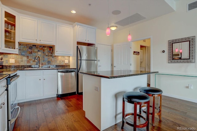 kitchen featuring a center island, dark hardwood / wood-style floors, decorative backsplash, white cabinets, and appliances with stainless steel finishes