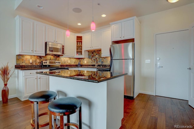 kitchen with pendant lighting, a center island, white cabinets, light hardwood / wood-style flooring, and stainless steel appliances