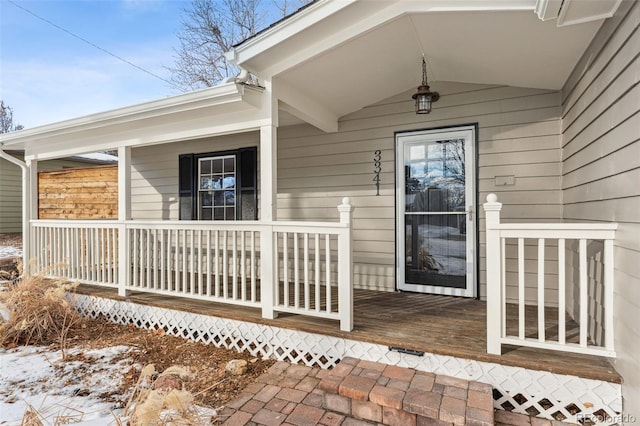 snow covered property entrance with a porch